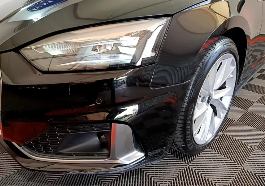 Gros plan sur l'avant droit noir d'une Audi A5 35 TFSI, mettant en valeur le phare LED et la jante alu.