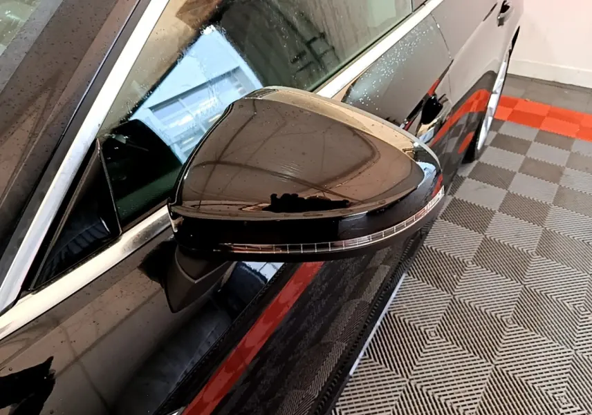Rétroviseur côté gauche noir brillant de l'Audi A5 35 TFSI 2021, vue rapprochée avec reflet et gouttes d'eau.
