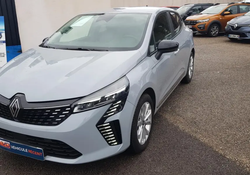 Renault Clio gris vue 3/4 avant droit, avec feux LED distinctifs et calandre noire brillante.