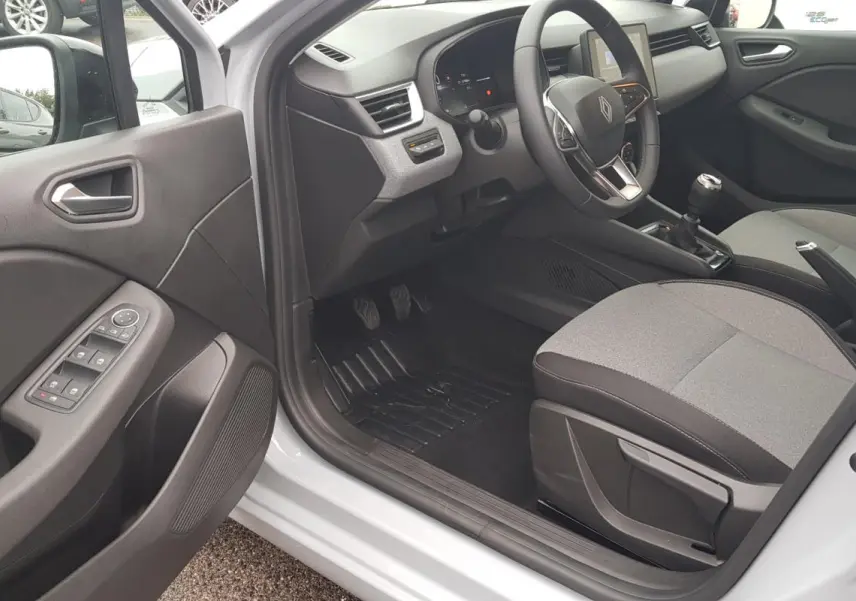 Vue intérieure côté conducteur de la Renault Clio gris 2025, montrant le volant, la boîte manuelle et les commandes de porte.