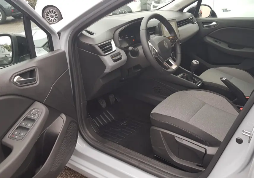 Vue intérieure côté conducteur de la Renault Clio gris 2025, montrant le tableau de bord et la boîte manuelle.