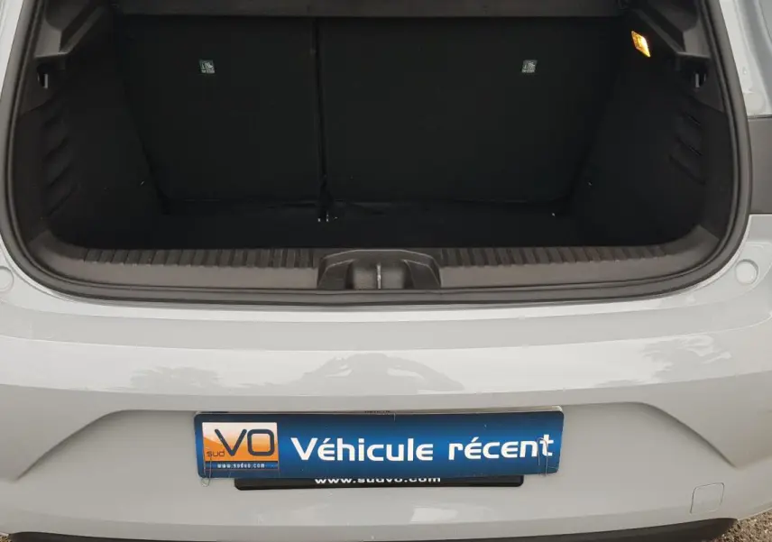 Vue arrière du coffre ouvert d'une Renault Clio gris clair, montrant l'espace de chargement vide et le pare-chocs.