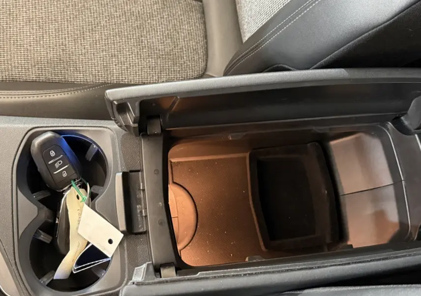 Vue rapprochée de la console centrale intérieure du Peugeot 5008 2019, avec accoudoir ouvert et clé dans porte-gobelets.