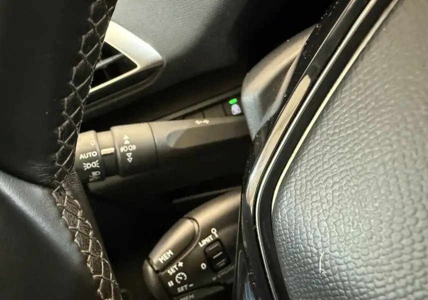 Gros plan sur le volant cuir noir et les commandes de régulateur de vitesse du Peugeot 5008 bleu, version Allure.