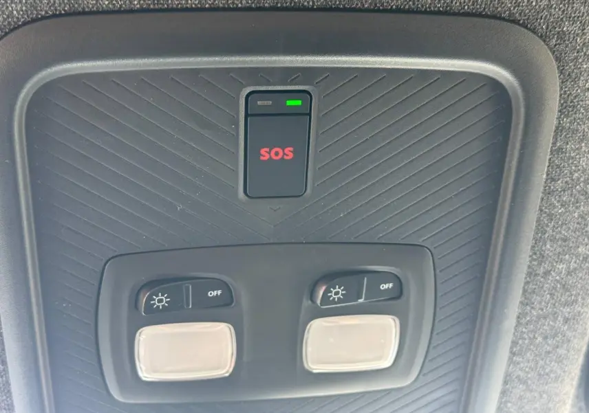 Vue rapprochée du plafonnier intérieur noir avec boutons d’éclairage et bouton SOS rouge du Dacia Duster 2026.
