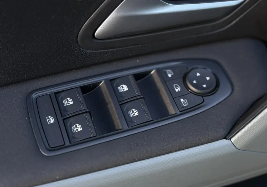 Gros plan sur les commandes de lève-vitres et rétroviseurs sur la porte côté conducteur du Dacia Duster kaki.