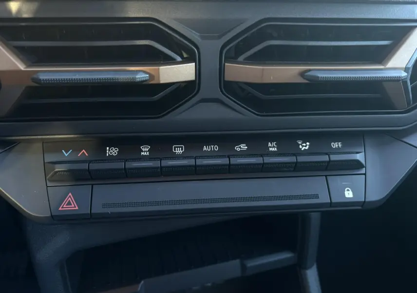 Vue rapprochée de la console centrale du Dacia Duster 2026, boutons de climatisation et aérateurs noirs avec inserts kaki.