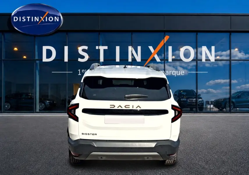 Vue arrière d'un Dacia Bigster blanc 2026 avec logo distinctif et feux arrière en forme de C, devant une vitrine Distinxion.