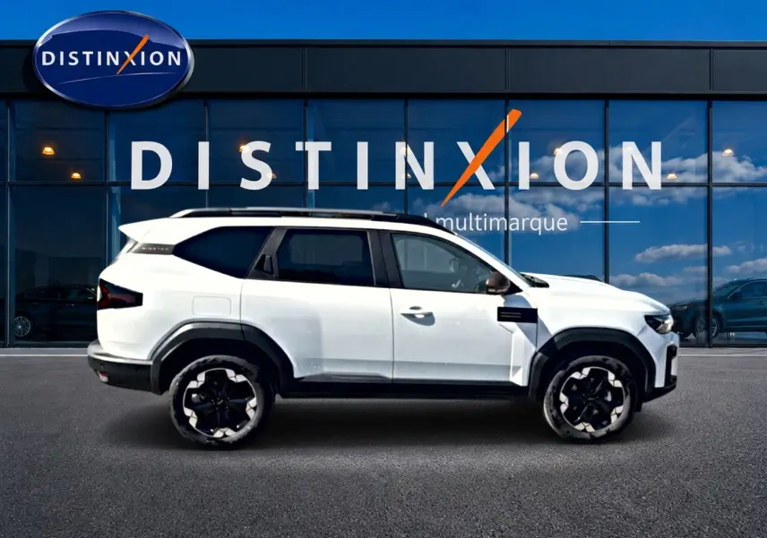 Profil droit du Dacia Bigster blanc 2026 avec jantes noires et toit contrasté devant une vitrine Distinxion multimarque.