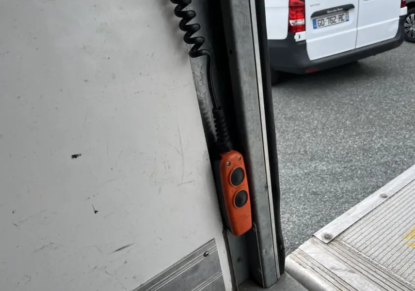 Gros plan sur la commande orange de la porte arrière ouverte d’un fourgon blanc Fiat Ducato Maxi Business.