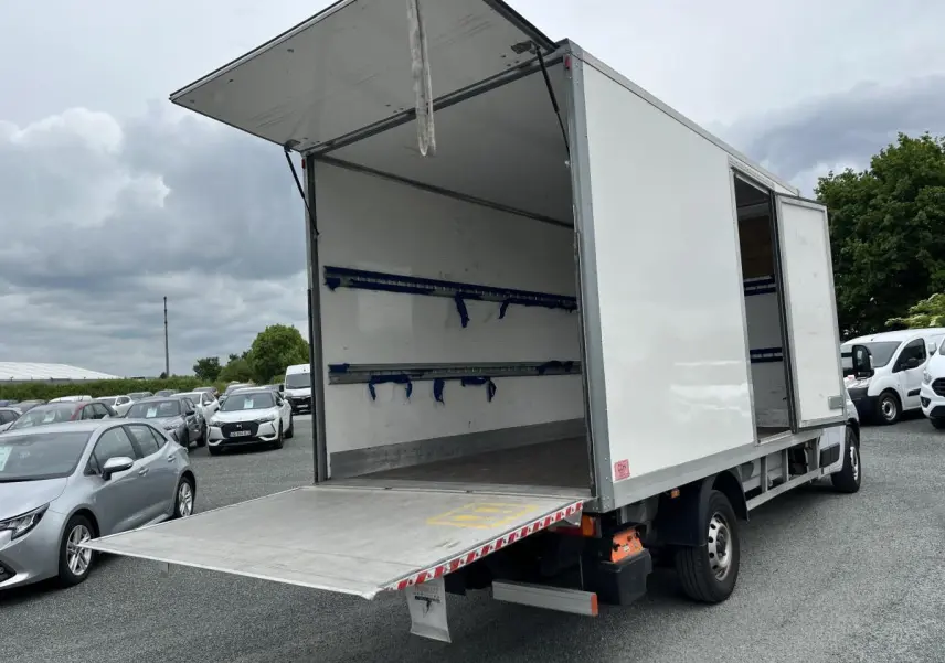 Fiat Ducato Maxi Business blanc vu 3/4 arrière droit avec porte latérale et hayon de chargement ouverts.