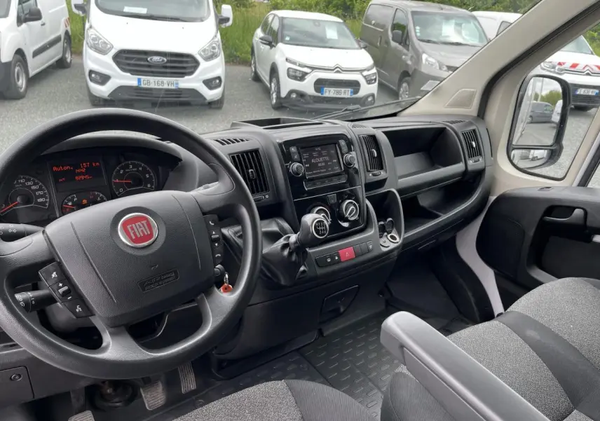 Vue intérieure côté conducteur du Fiat Ducato Fourgon blanc 2021, tableau de bord avec volant multifonction et levier de vitesses manuel.