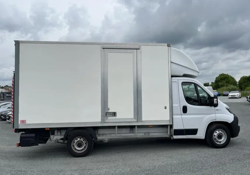 Fiat Ducato Fourgon Maxi Business blanc vu de profil côté gauche avec grande caisse de chargement et porte latérale.