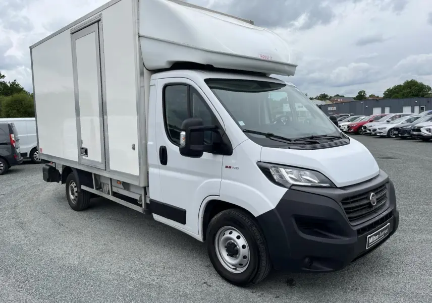 FIAT Ducato Fourgon blanc vue 3/4 avant droit avec grande caisse de chargement et capucine sur toit.