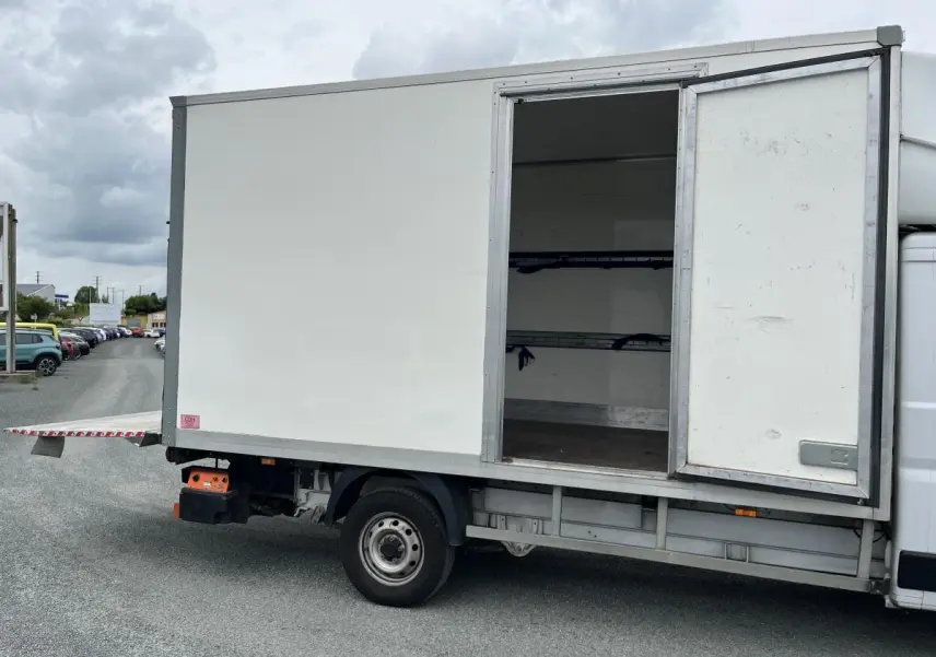 Vue latérale droite d'un FIAT Ducato Fourgon blanc avec porte latérale ouverte et hayon arrière déployé.