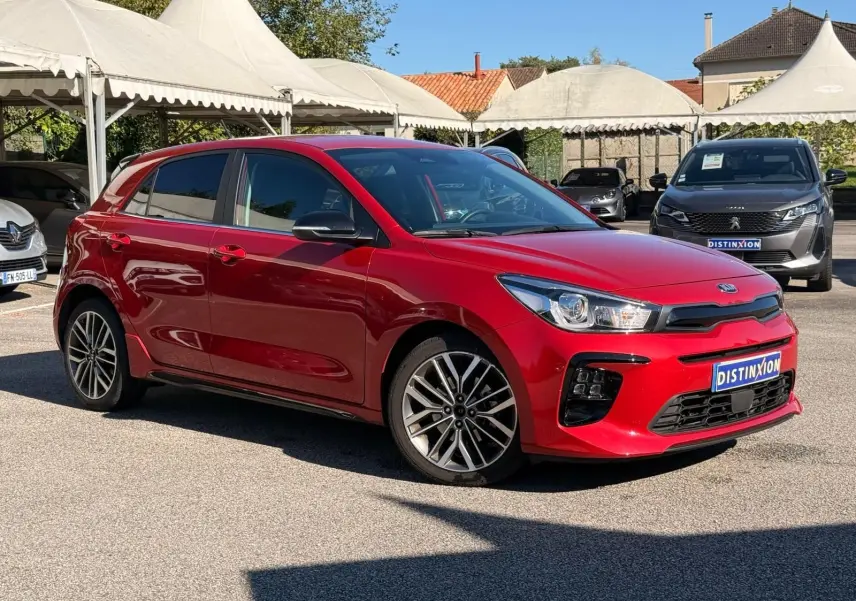 KIA RIO rouge grenadine vue 3/4 avant droit, avec jantes alliage et calandre noire distinctive.