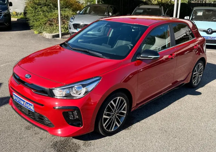 KIA RIO rouge grenadine vue 3/4 avant droit, avec jantes alliage et rétroviseurs noirs brillants.