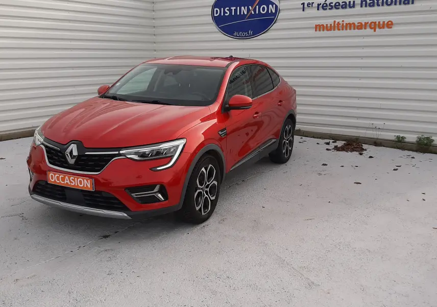Renault Arkana 1.6 E-TECH rouge Flame en 3/4 avant droit, avec jantes bi-ton et calandre noire distinctive.