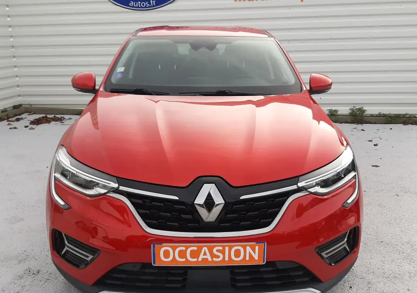 Vue frontale d'un Renault Arkana rouge flame 2021 avec calandre noire et plaque "OCCASION" visible.