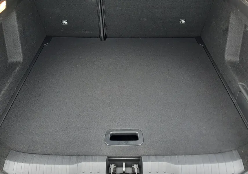 Coffre vide vu de l'arrière d'un Renault Arkana 1.6 E-TECH 145 Intens rouge Flame, revêtement noir uniforme.