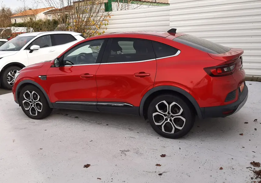 Renault Arkana rouge Flame en vue de profil côté gauche, soulignant sa silhouette coupé et ses jantes originales.
