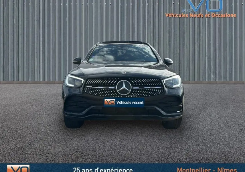 Vue frontale d'un Mercedes GLC 300 de 2020 gris anthracite avec calandre AMG et phares LED allumés.
