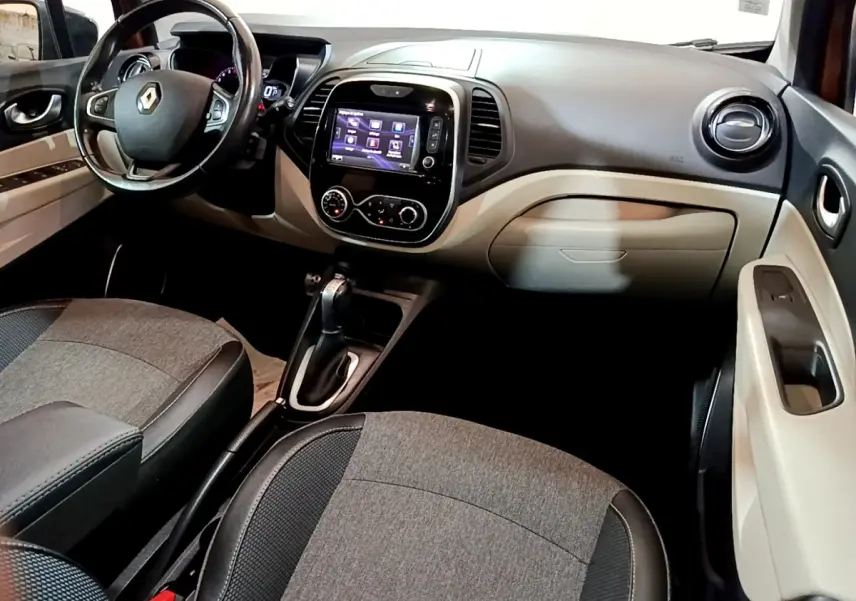 Intérieur beige et noir du Renault Captur Intens 2019, vue de profil côté conducteur avec tableau de bord et écran tactile.
