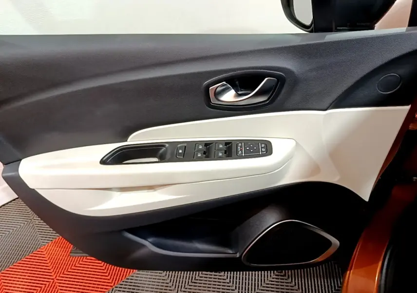 Intérieur côté gauche de la porte avant d'un Renault Captur orange, avec commandes électriques et habillage bicolore noir et beige.