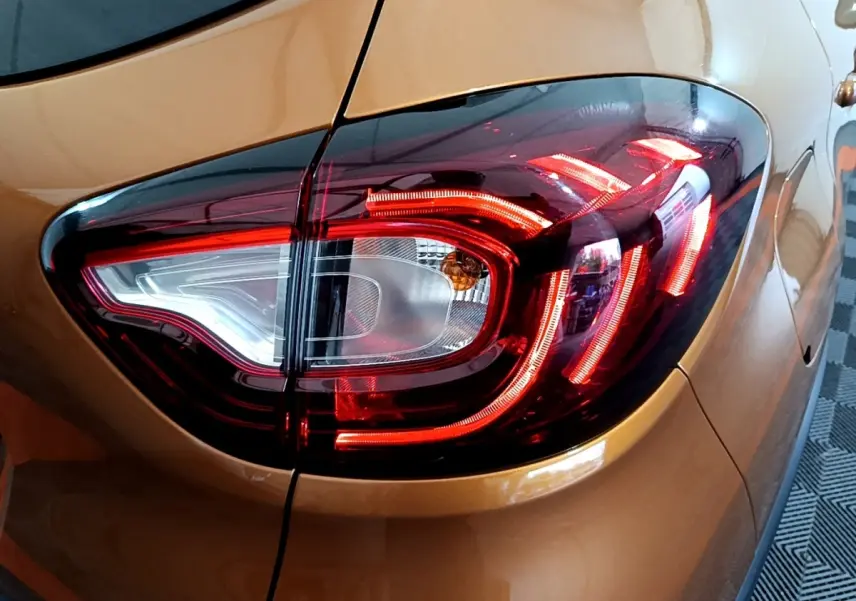Gros plan sur le feu arrière droit rouge et blanc du Renault Captur Intens orange 2019, soulignant ses lignes LED distinctives.