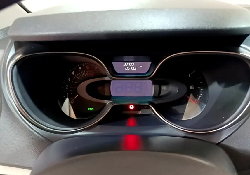 Vue rapprochée du tableau de bord numérique du Renault Captur Intens orange, affichant compteur et indicateurs lumineux.