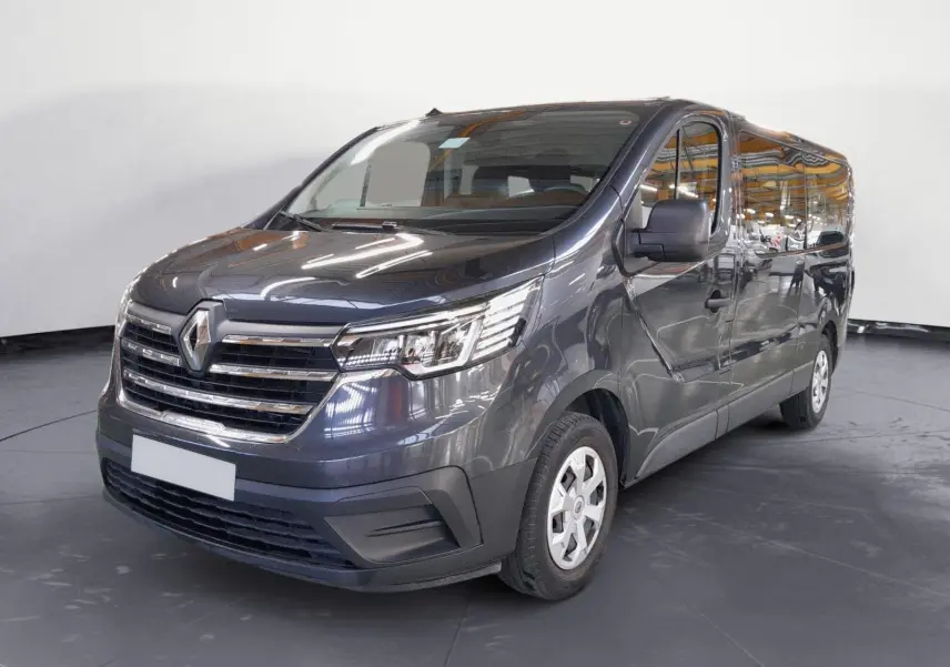 Renault Trafic Combi gris comète en 3/4 avant droit, mettant en valeur sa calandre chromée et ses grandes vitres latérales.