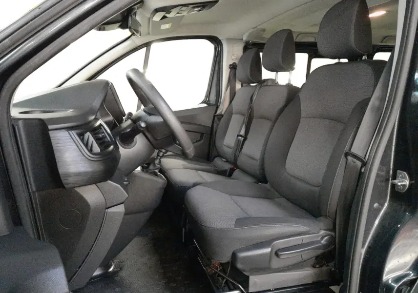 Vue intérieure côté conducteur du Renault Trafic Combi gris comète, montrant les sièges avant et le tableau de bord.