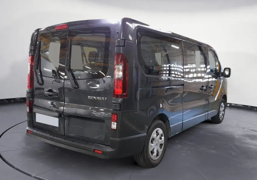 Vue 3/4 arrière droite du Renault Trafic Combi gris comète, mettant en valeur ses grandes vitres latérales et portes arrière battantes.