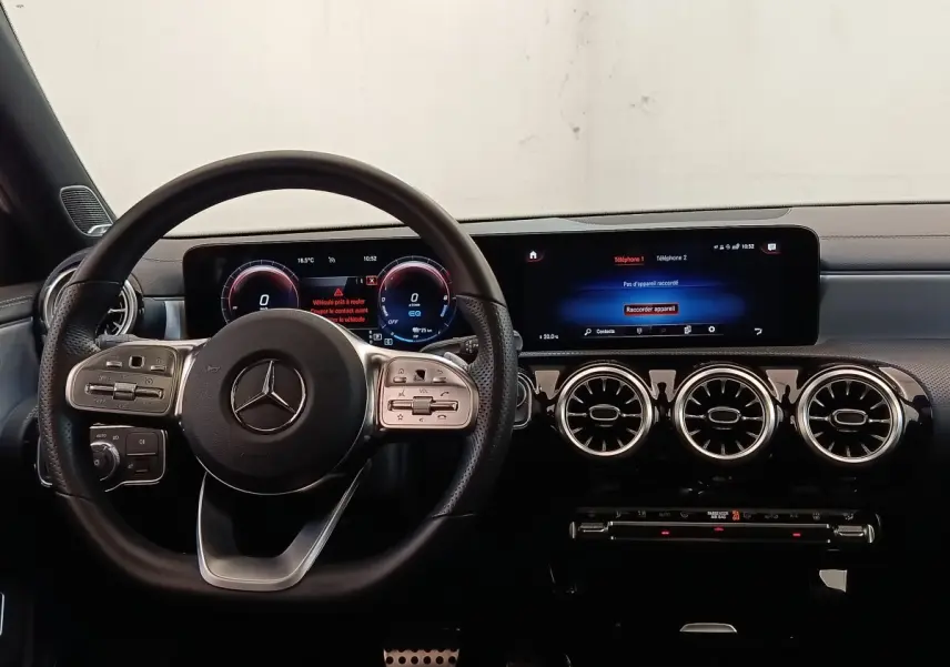 Vue intérieure du tableau de bord et volant cuir alu multifonctions de la Mercedes Classe A 250 e AMG Line blanche de 2021.