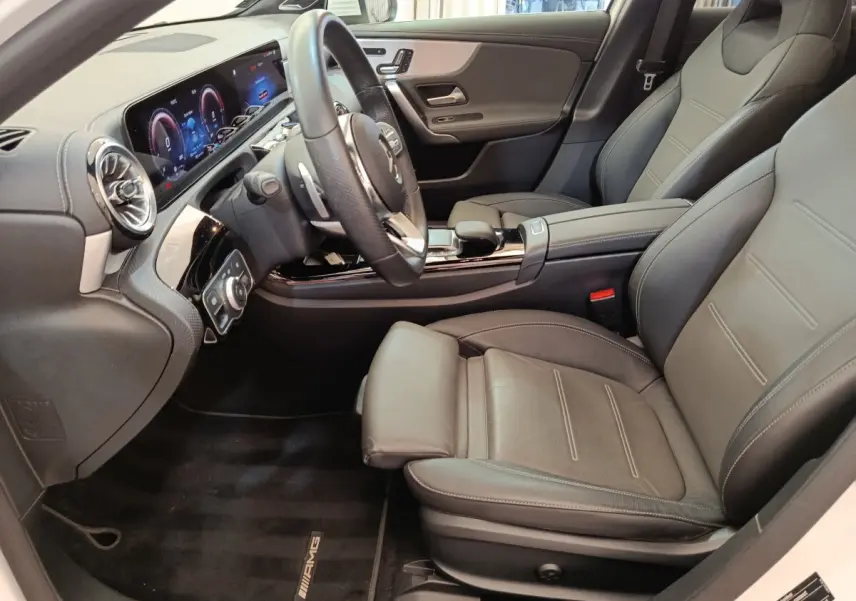 Vue intérieure côté conducteur de la Mercedes Classe A 250 e AMG Line 2021 avec sièges cuir noirs et tableau de bord numérique.