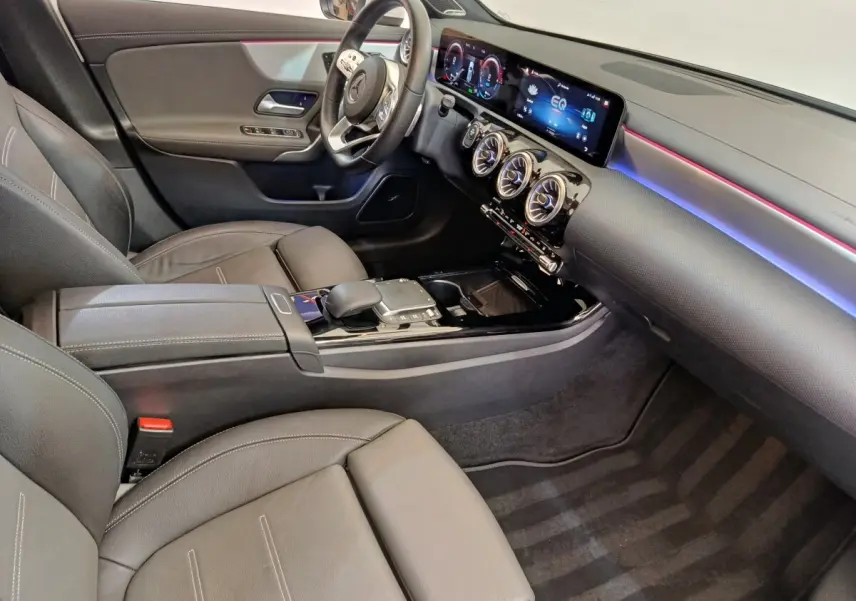 Vue intérieure côté conducteur de la Mercedes Classe A 250 e AMG Line 2021, avec tableau de bord numérique et éclairage d’ambiance coloré.