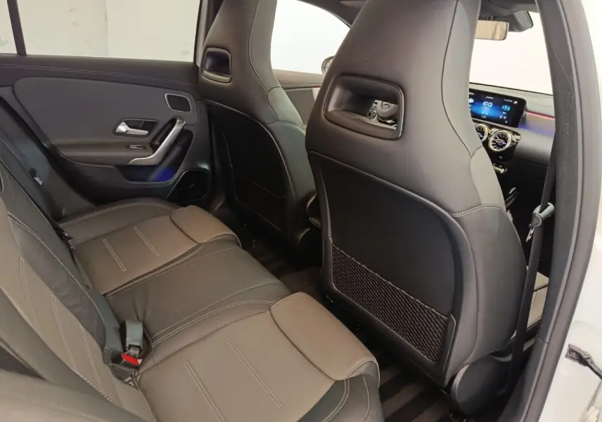 Vue intérieure arrière droite de la Mercedes Classe A 250 e AMG Line blanche, sièges en cuir noir et tableau de bord digital.
