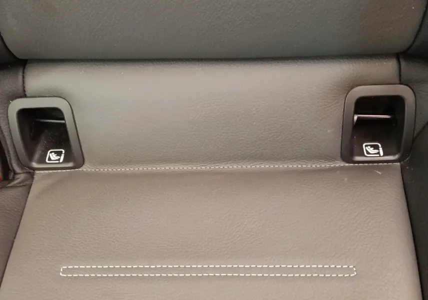 Gros plan sur les ancrages ISOFIX noirs intégrés dans la banquette arrière en cuir gris foncé d'une Mercedes Classe A blanche.
