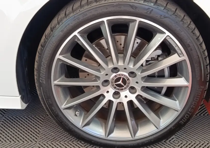 Gros plan sur la jante AMG argentée de la Mercedes Classe A blanche, avec pneu Bridgestone visible.