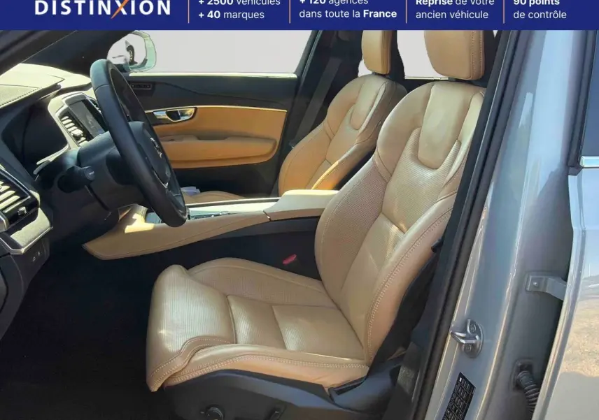 Vue intérieure côté conducteur du Volvo XC90 gris 2024, mettant en valeur les sièges en cuir beige et le tableau de bord moderne.