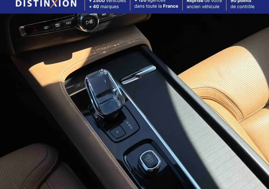 Gros plan sur la console centrale beige du Volvo XC90 2024 avec levier de vitesses cristal et bouton démarrage.