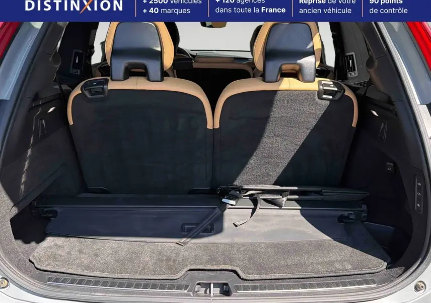 Vue du coffre arrière ouvert du Volvo XC90 gris, montrant la 3ème rangée de sièges rabattus et un cache-bagages déployé.