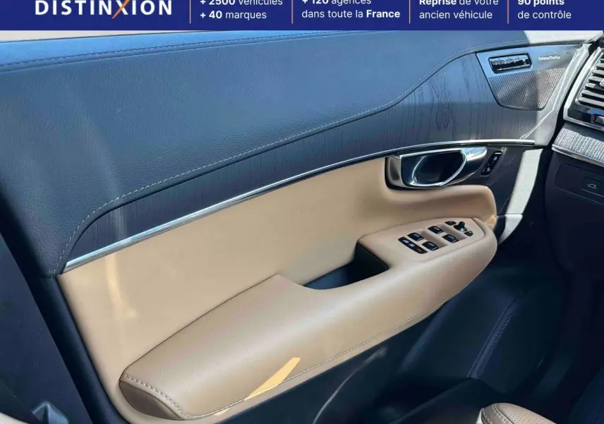 Détail de la porte avant droite intérieure beige et noire du Volvo XC90 2024 avec commandes de vitres et insert carbone.