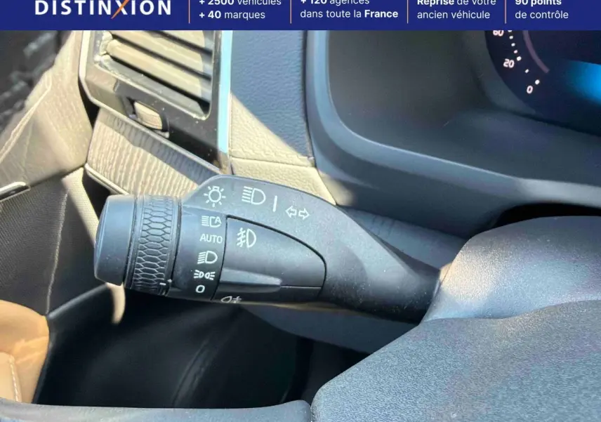 Gros plan sur la commande des feux à gauche du volant dans l’habitacle gris du Volvo XC90 gris 2024.