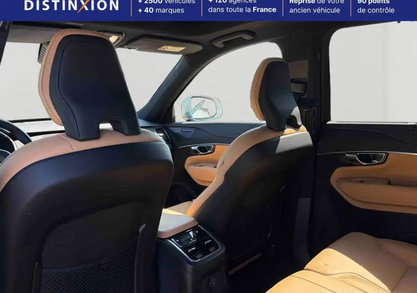 Vue intérieure arrière du Volvo XC90 2024 montrant les sièges en cuir bicolore beige et noir avec console centrale et toit ouvrant panoramique.