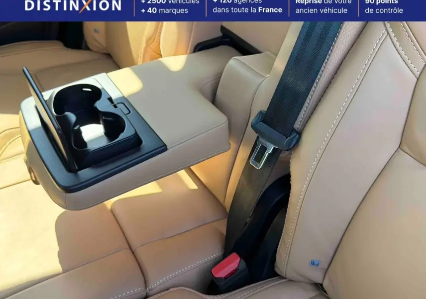 Détail de l'accoudoir central arrière beige avec porte-gobelets déployé dans le Volvo XC90 2024.