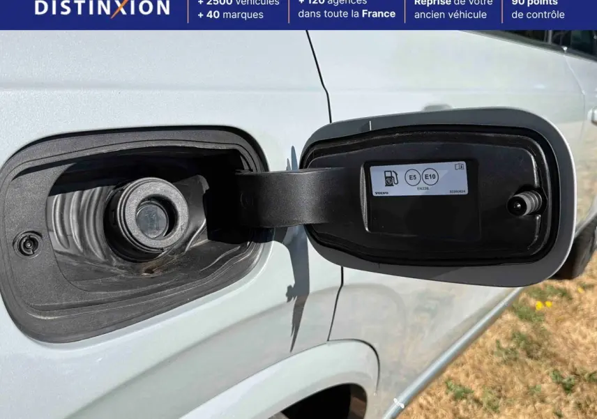Vue rapprochée du bouchon de réservoir ouvert côté gauche sur un Volvo XC90 gris clair 2024 hybride rechargeable.