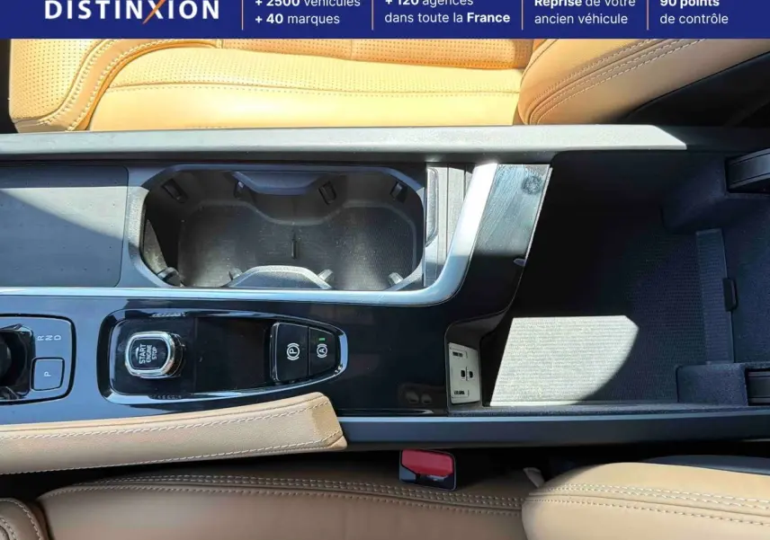 Vue rapprochée de la console centrale beige du Volvo XC90 T8 hybride avec bouton start/stop et porte-gobelets.