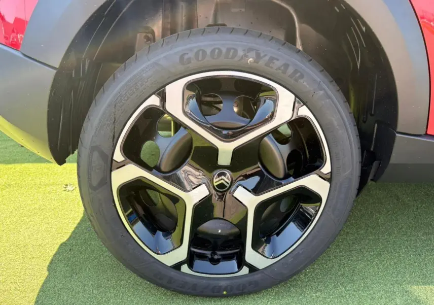 Gros plan sur la roue avant droite d'une Citroën C3 rouge Elixir avec jante noire et argentée au design moderne.