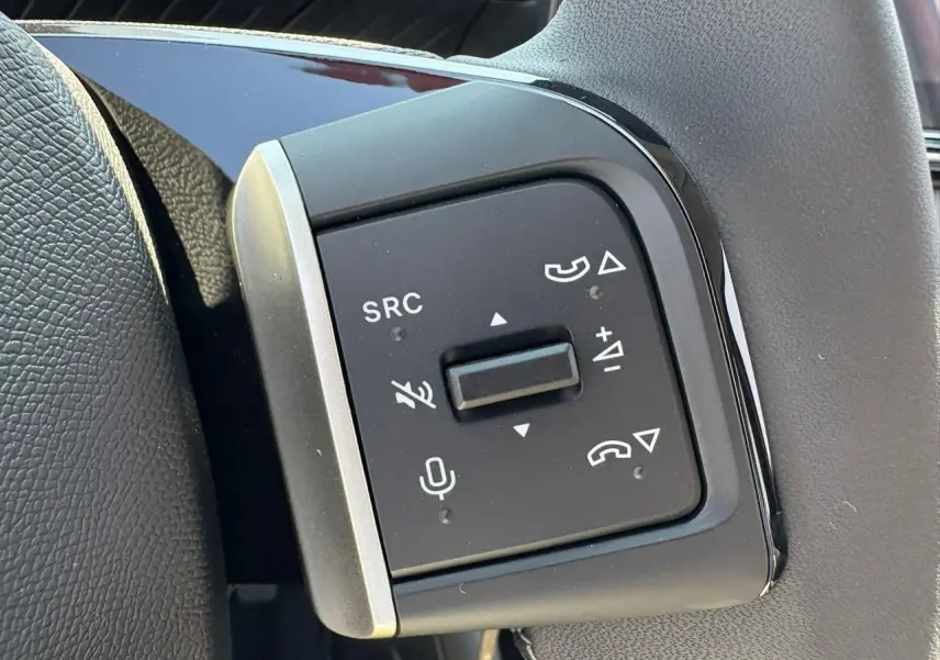 Gros plan sur les commandes au volant gauche du Citroën C3 2025 rouge Elixir avec toit noir.